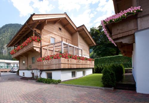a building with a balcony with red flowers on it at Chalet - Appartements Julitta in Mayrhofen