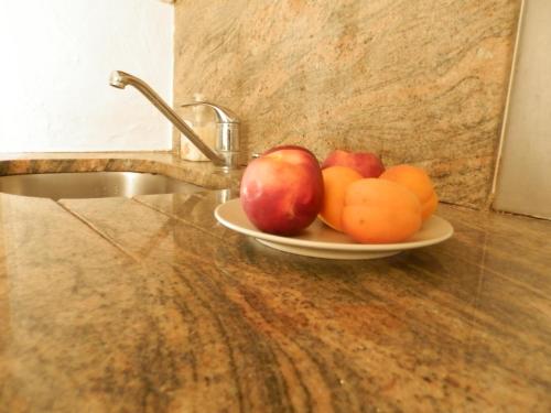 a plate of fruit on a counter next to a sink at Les Pins . 2 p calme et terrasse in Nice