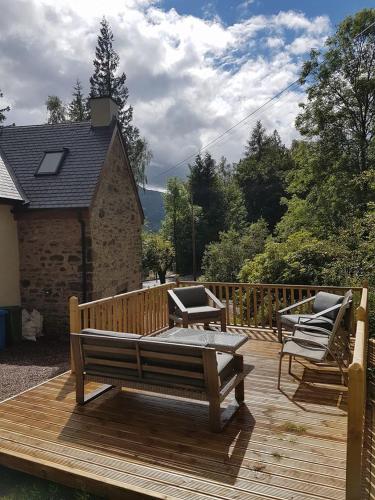 a wooden deck with two benches and a table at The Armoury in Glenfinnan
