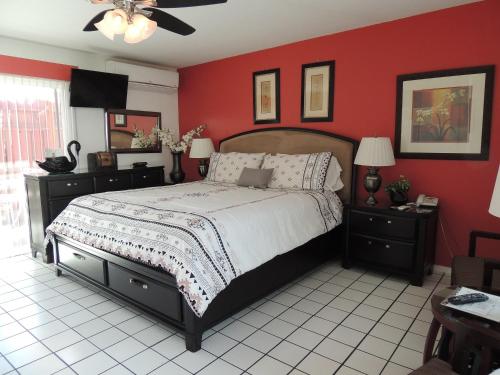 1 dormitorio con cama y pared roja en Casa Larrea Inn en Palm Desert