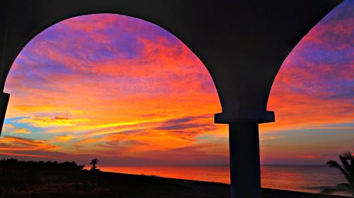 a sunset seen through an archway at the beach at Villa Star of the Sea in Barra de Navidad