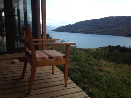 a wooden chair sitting on a porch with a view of a lake at Mallin Colorado Ecolodge in Aldana