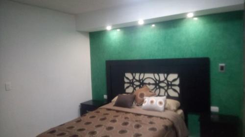 a green bedroom with a bed with a teddy bear on it at Habitación Puebla Purpura in Puebla