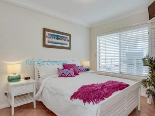 a white bedroom with a large bed and a window at Ocean Pines Apartments 4 in The Entrance