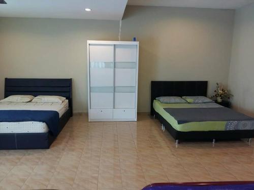 a bedroom with two beds and a white cabinet at Port Dickson Holiday Home Villa in Port Dickson
