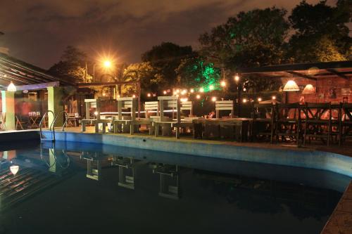 a swimming pool at night with a table and chairs at Pura vida Mae Hostel in Yerba Buena