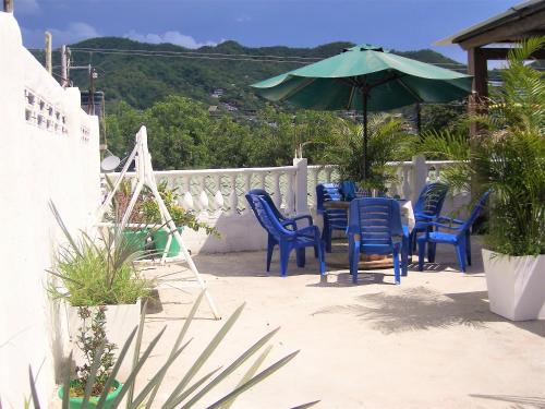a patio with blue chairs and an umbrella at Hostal Palohe Taganga in Taganga