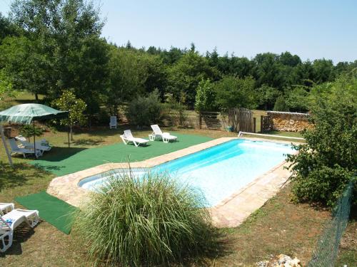 une piscine avec deux chaises et un parasol dans l'établissement Le Clos de Carmensac, à Meyrals