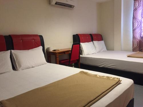 a hotel room with two beds and a table at Ophir Inn in Skudai