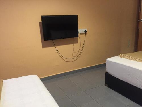 a room with two beds and a tv on a wall at Ophir Inn in Skudai
