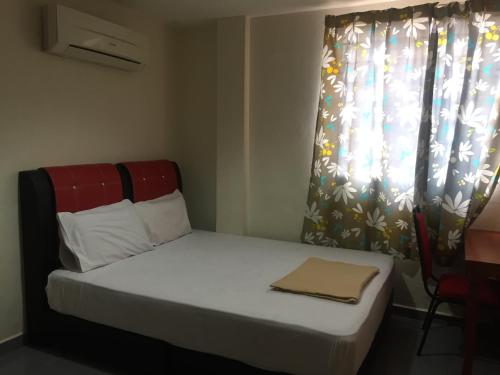 a small bed in a room with a window at Ophir Inn in Skudai