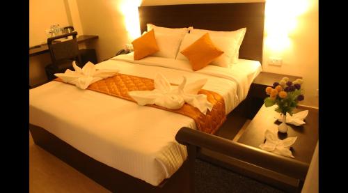 a hotel room with two beds with flowers on them at Hotel Yamuna in Adūr