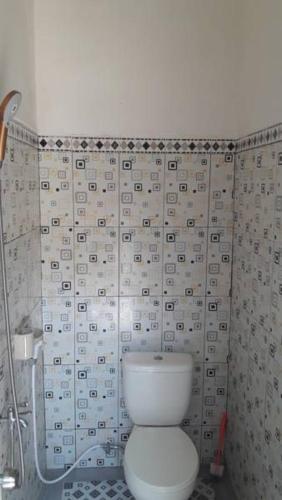 a bathroom with a toilet and a wall with tiles at Arriani Homestay in Karimunjawa