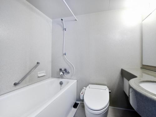 a bathroom with a toilet and a tub and a sink at Hotel Pearl City Sapporo in Sapporo