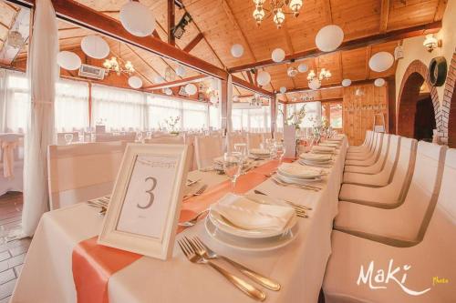 a long dining room with white tables and chairs at Vándor Vigadó in Zalaegerszeg