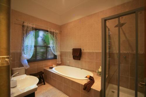 a bathroom with a tub and a sink and a shower at Summer Garden Guest House (The Palms) in Benoni