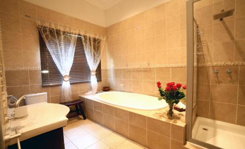 a bathroom with a tub and a vase of flowers at Summer Garden Guest House (The Palms) in Benoni