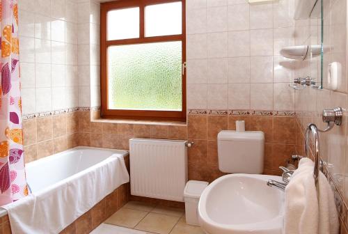 a bathroom with a tub and a toilet and a sink at Pihenőkereszt Panzió in Sopron
