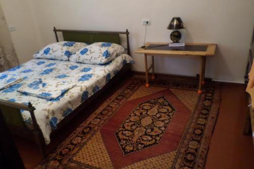 a bedroom with a bed and a table and a rug at Spandaryan House in Yeghegnadzor