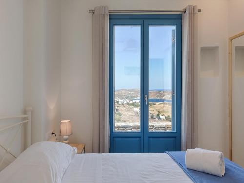 a bedroom with a blue door and a window at Serifos Blue in Rámos