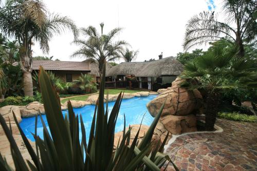 a resort with a swimming pool and a house at Summer Garden Guest House (The Palms) in Benoni