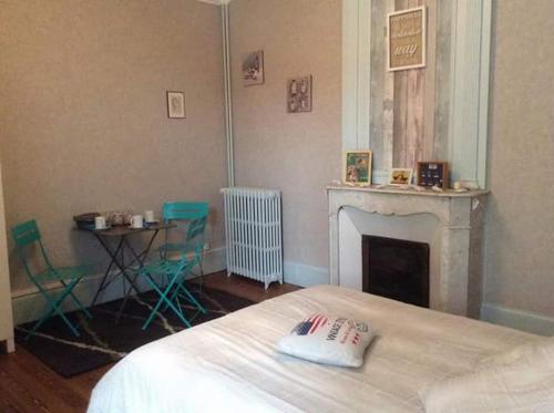 a bedroom with a bed and a fireplace and a table at la Tourelle en Normandie in Saint-Pierre-Église