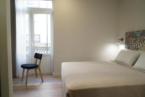 a bedroom with a bed and a chair and a window at MD Design Hotel - Portal del Real in Valencia