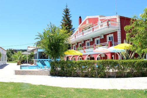 a large red building with umbrellas and a swimming pool at Crystal in Kavos