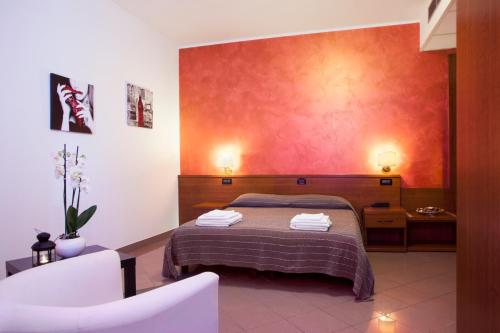 ガルツィニャーノにあるHotel L'Incontroの赤い壁のベッドルーム1室