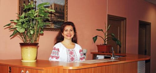a woman sitting at a counter with a potted plant at Hotel Nova in Kyiv