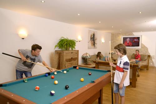 a man and a boy playing pool in a living room at Hotel Bichlhof in Reit im Winkl
