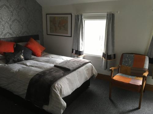 a bedroom with a bed and a chair and a window at Erin Cottage in Derry Londonderry