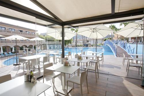 a restaurant with tables and chairs and a swimming pool at Mon Port Hotel & Spa in Port d’Andratx