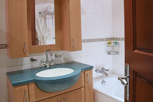 Imperial Resort Beach Hotel في عنتيبي: حمام مع حوض استحمام ومغسلة زرقاء