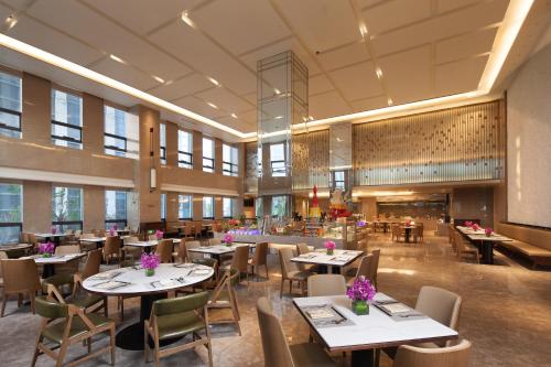 a restaurant with tables and chairs in a room at Ramada Jinan in Jinan