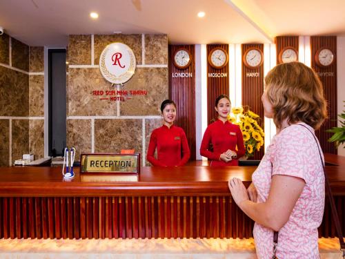 a woman standing in front of a bar with two girls at Red Sun Nha Trang Hotel in Nha Trang