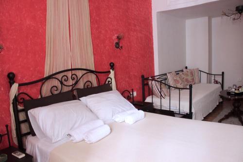 two beds in a room with red walls at Filyra Pension in Nafplio