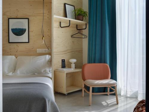a bedroom with a bed and a chair at Talo Urban Rooms in Donostia-San Sebastián