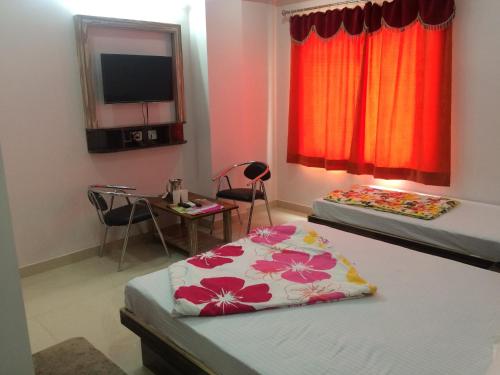 a room with two beds and a table and a television at Hotel Thikana Palace in Jaipur