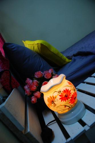 eine Vase mit Blumen auf einem Tisch neben einem Bett in der Unterkunft Hotel An Nhien in Buon Ma Thuot