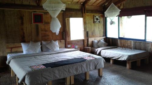 a bedroom with two beds in a room with windows at Mu Cang Chai Eco Lodge in Nam San