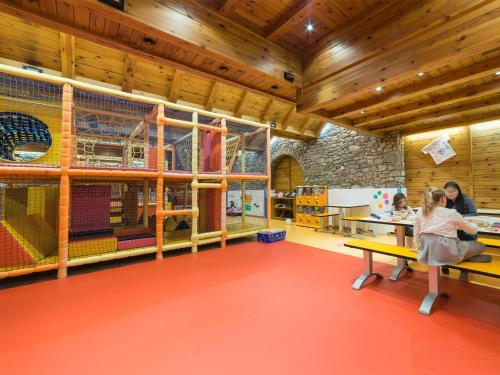 a childrens play room with wooden ceilings and wooden floors at Sport Hotel Village in Soldeu