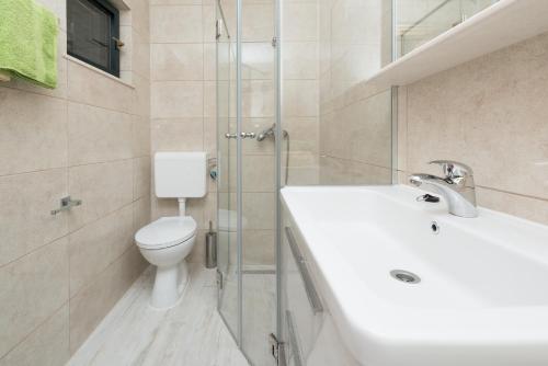 a bathroom with a toilet and a sink and a shower at City Center Suites - Apartment with Terrace and Private Pool in Cavtat