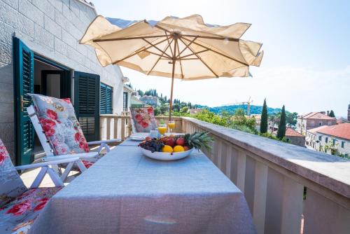 a bowl of fruit on a table on a balcony with an umbrella at City Center Suites - Apartment with Terrace and Private Pool in Cavtat