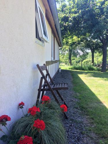 a wooden bench sitting outside of a house with red flowers at La Boulangerie in Romagny