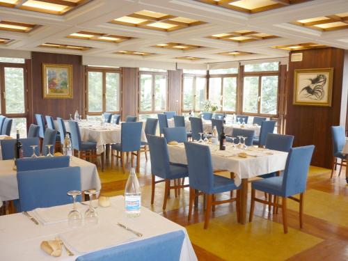 une salle à manger avec des tables blanches et des chaises bleues dans l'établissement Hotel Candanchú, à Candanchú