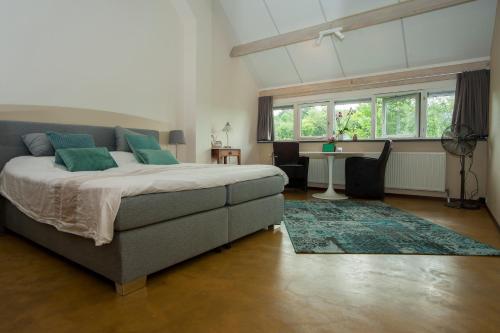 a bedroom with a bed and a table and windows at Hof van Bommerig in Mechelen