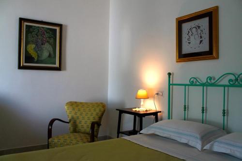 a bedroom with a bed and a chair and a lamp at Kennedy House in Novoli
