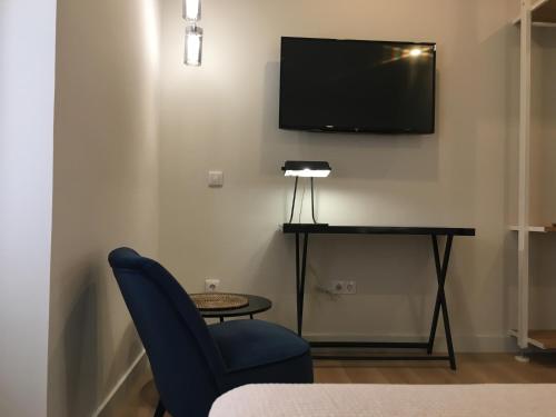 a room with a blue chair and a tv on a wall at MD Design Hotel - Portal del Real in Valencia