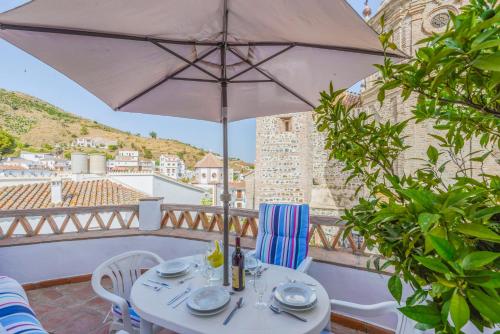 a white table with an umbrella on a balcony at "El Porton" (El Borge ,Malaga). in Borge